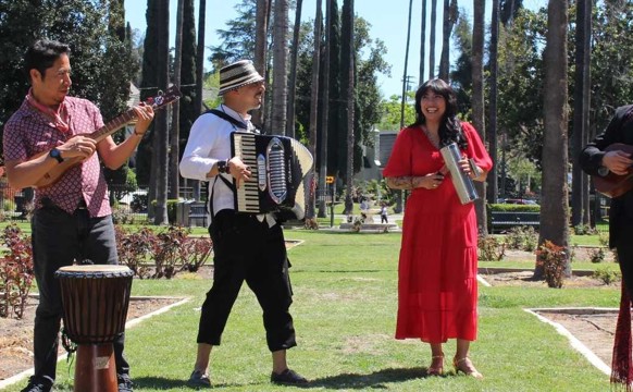 El Santo Golpe band standing together holding their instruments outside on a courtyard
